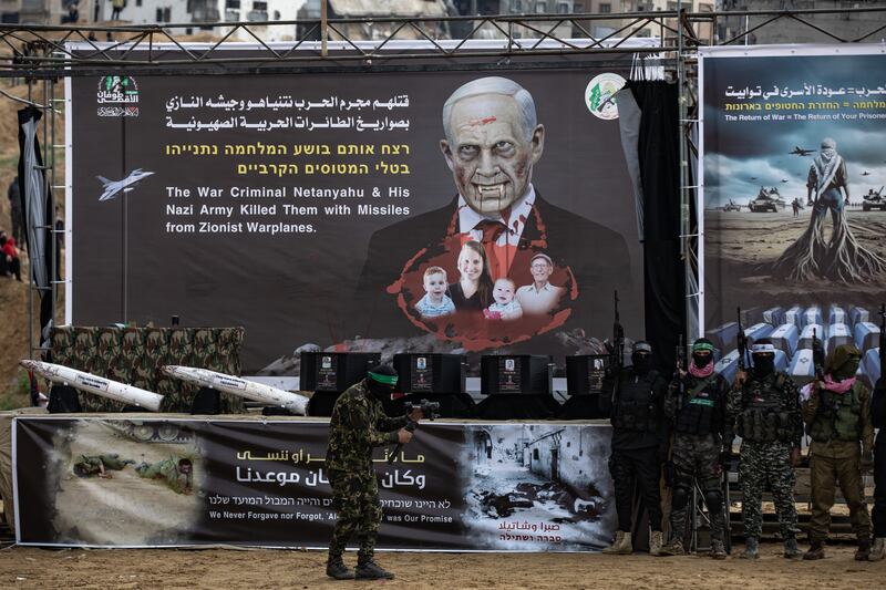 A Hamas fighter stands in front of a banner near the coffins containing the bodies of Sheri Bibas, her two children, Ariel and Kfir, and Oded Lifshitz. Photograph: Haitham Imad/EPA
