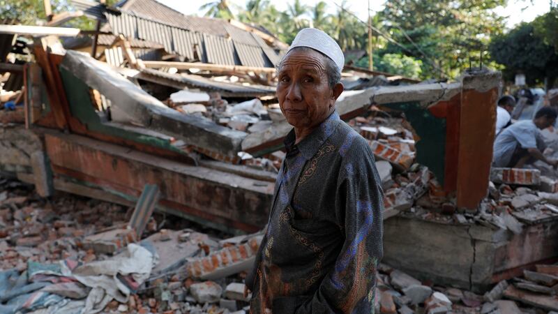 A villager walks through a collapsed house after an earthquake hit Lombok Island in  Indonesia. Photograph: Beawiharta/Reuters