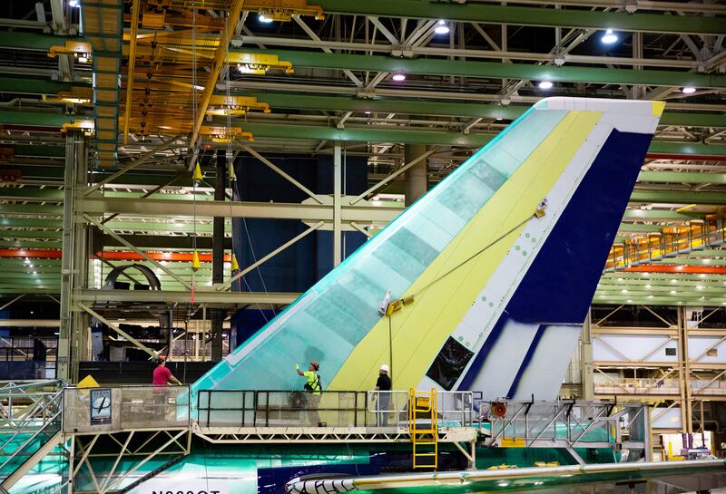 Workers unhook crane cables from the vertical fin as it is attached to the plane. Photograph: Lindsey Wasson/The New York Times