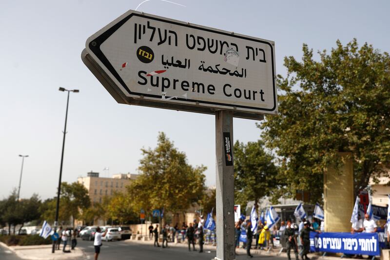 A road sign is seen near right-wing activists protesting against Israel's supreme court during a hearing of petitions against the reasonableness standard law  in Jerusalem. Photograph: Atef Safadi/EPA