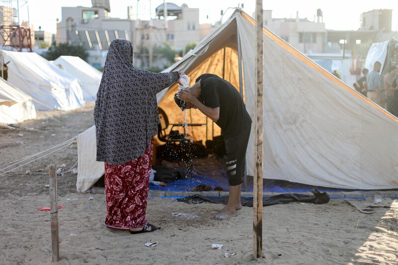  A woman pours water on her son in a shelter set up  in the Khan Younis training centre in the southern Gaza Strip. Photograph: Yousef Masoud/New York Times