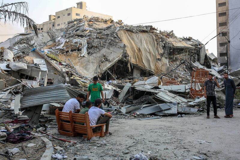 Palestinian citizens inspect the damage after the Watan Tower, which contains offices and shops, was bombed by Israeli warplanes in downtown Gaza city on Sunday. Photograph: Samar Abu Elouf/The New York Times
                      