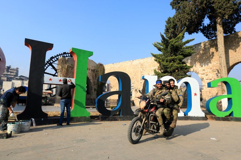 Fighters drive past an "I Love Hama" sign repainted in the colours of Syria's opposition flag in the city on Friday. Photograph: Bakr Al Kassem/AFP via Getty