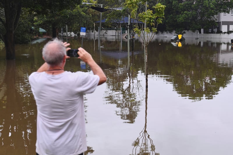 A resident takes photos of a flooded road, in Oxley, Brisbane. Photograph: Jono Searle/AAP Image/AP