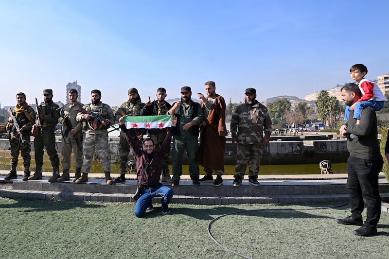 A man poses for a photo with anti-government fighters holding a Syrian opposition flag at Umayyad Square in Damascus. Photograph: Louai Beshara/AFP/Getty Images