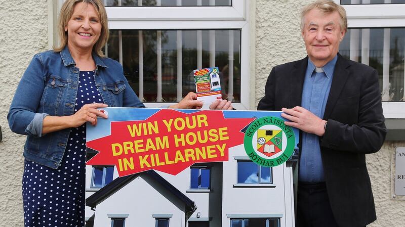 Fr Jim Kennelly buys a ticket for the raffle of a new house from Boherbue National School principal Marie Casey. To break even, she needs to sell 4,500 tickets at €100 each to cover the legal fees, advertising and promotion.  Photograph: Sheila Fitzgerald