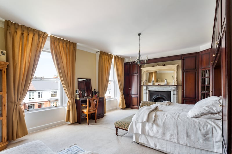 The main bedroom has two shuttered sash windows and an original fireplace