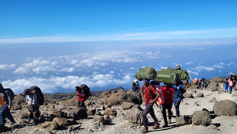 Tanzanian porters carrying luggage up Kilimanjaro. Photograph: Shauna Bowers