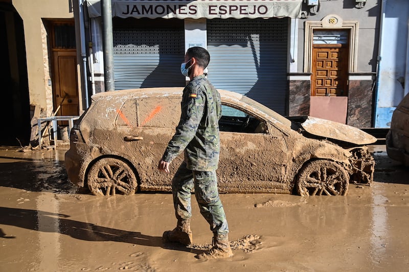 A soldier walks past a flood-damaged car in Massanassa, in the region of Valencia, eastern Spain. Photograph: JOSE JORDAN/AFP via Getty Images