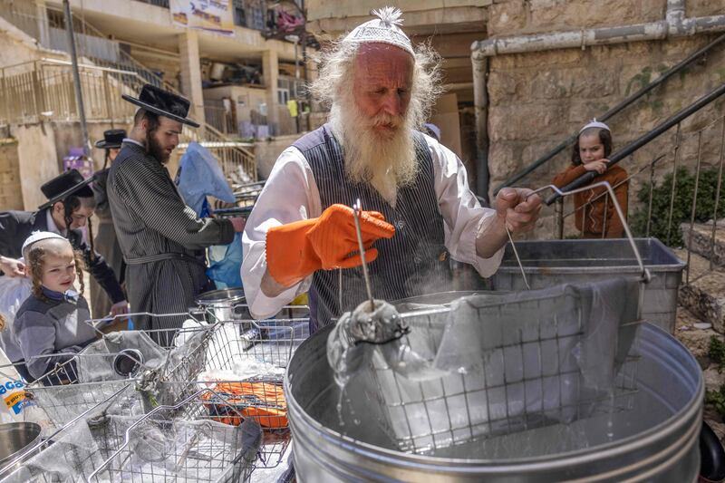 An Ultra-Orthodox Jewish man dips cooking utensils in boiling water to remove traces of chametz in Jerusalem's Mea Shearim neighbourhood. Photograph: Menahem Kahana/AFP/Getty