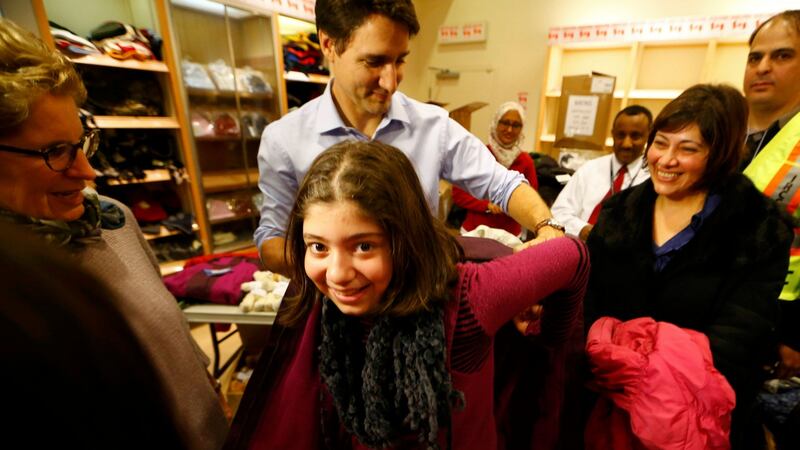 Canada’s prime minister Justin Trudeau helps a young Syrian refugee try on a winter coat after she arrived with her family from Beirut at the Toronto Pearson International Airport. Photograph: Mark Blinch/Reuters