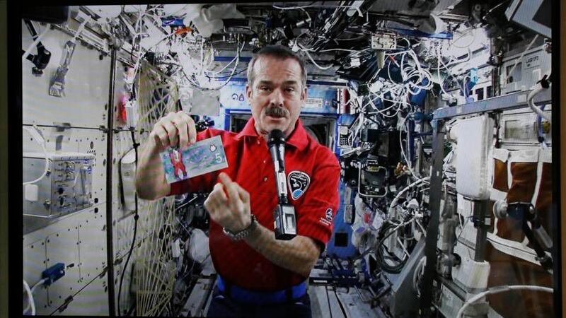 Canadian Space Agency astronaut Chris Hadfield holds the new Canadian $5 bill, made of polymer, while on a mission in space