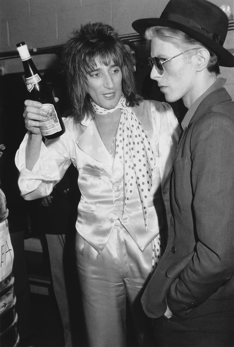 Rod Stewart holds a bottle of Blue Nun wine while talking to David Bowie backstage at Madison Square Garden. Photograph: Hulton Archive/Getty Images