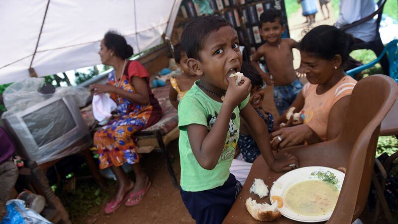 A Sri Lankan boy affected by torrential floods  eats a meal at a road camp in the  Kelaniya suburb of  Colombo on Wednesday. Photograph: AFP/Getty Images