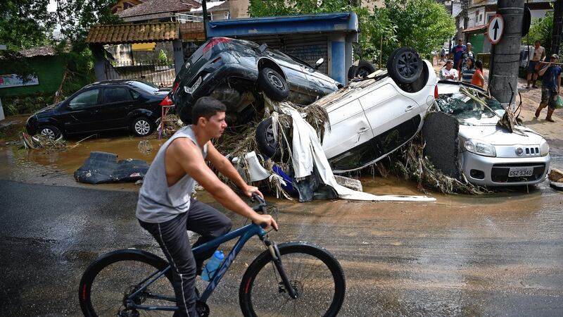 A man rides his bicycle past cars destroyed by a flash flood in Petrópolis, Brazil. Photograph: Carl de Souza/AFP via Getty Images