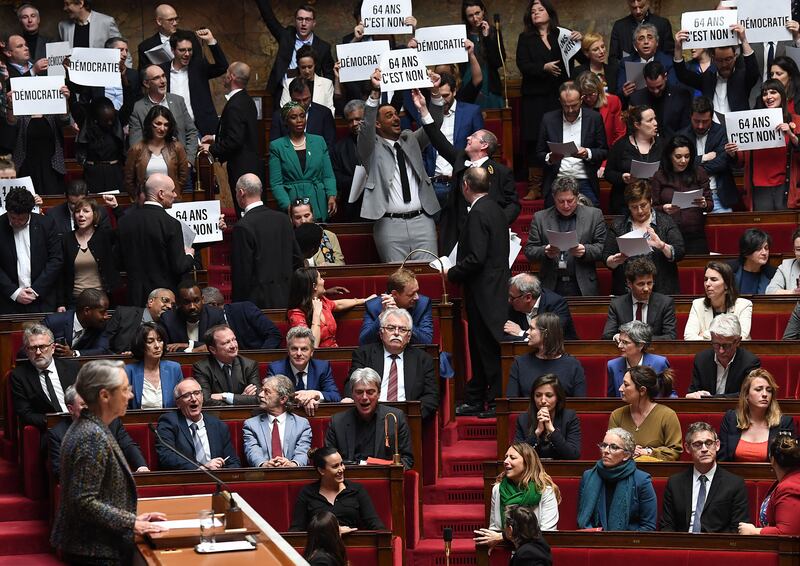 Left-wing Nupes deputies hold up placards saying “No to age 64″  as French prime minister Elisabeth Borne confirms that the government's pension reform plan is to be passed by decree. Photograph: Alain Jocard/Getty Images