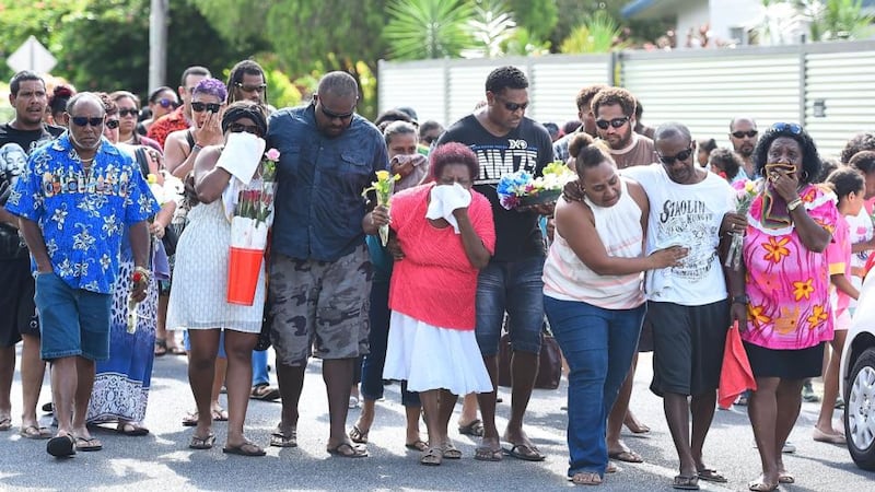 Family members mourn as they walk to a memorial which is located in the park next the home of a multiple stabbing in the suburb of Manoora on Sunday. Photograph: Getty