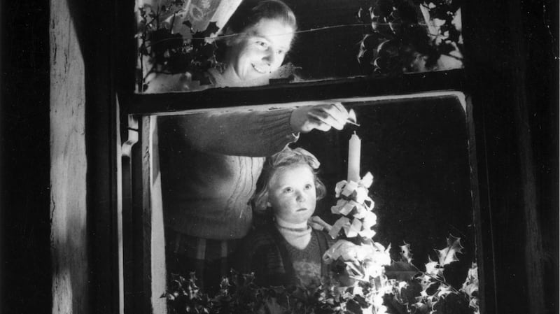 A young girl watches her mother light a candle in their window  c1955. Photograph: Three Lions/Getty Images