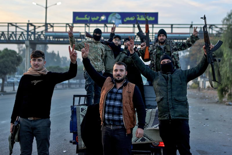 Syrian rebel fighters celebrate at the entrance of Homs province early on December Sunday. Hayat Tahrir al-Sham (HTS) and allied anti-government factions have since November 27th swept swathes of the country from government control. Photograph: by Aaref Watad/AFP via Getty Images