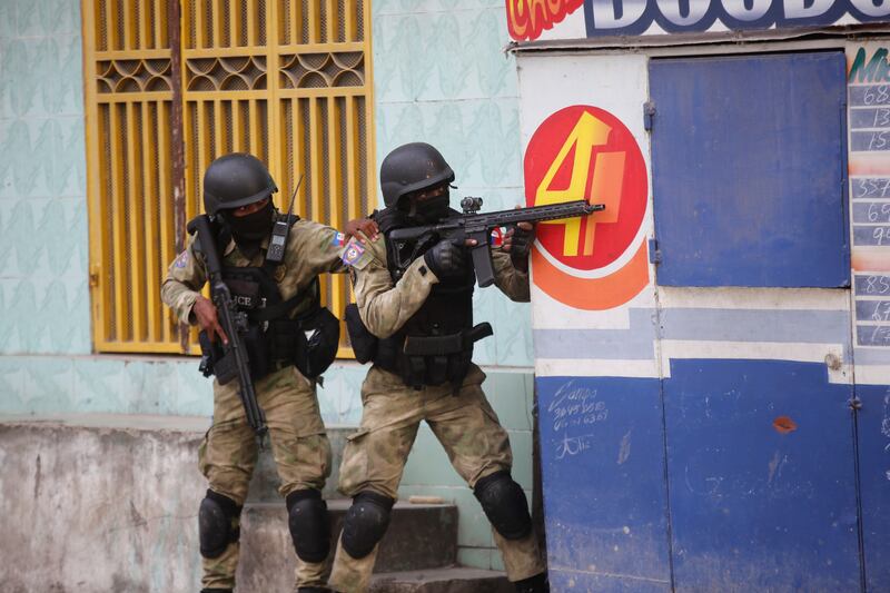 Police take cover during an anti-gang operation in Port-au-Prince. Photograph: Odelyn Joseph/AP