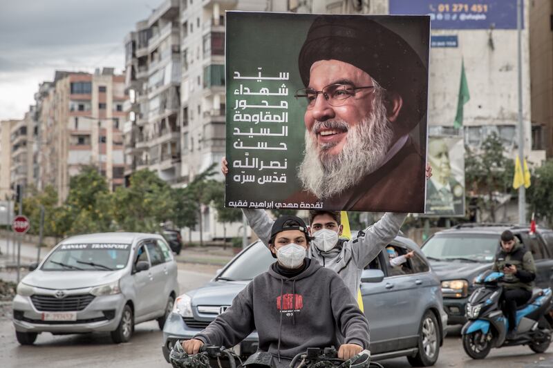 Two boys hold up a poster of assassinated Hizbullah leader Hassan Nasrallah. Photograph: Sally Hayden. 