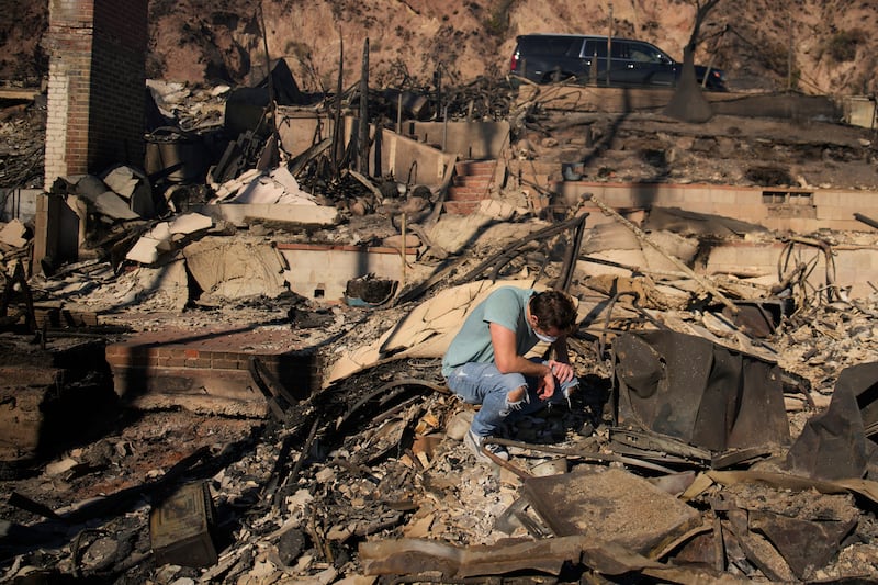 Luke Dexter kneels as he sifts through the remains of his father’s fire-ravaged beachfront property in the aftermath of the Palisades fire. Photograph: John Locher/AP