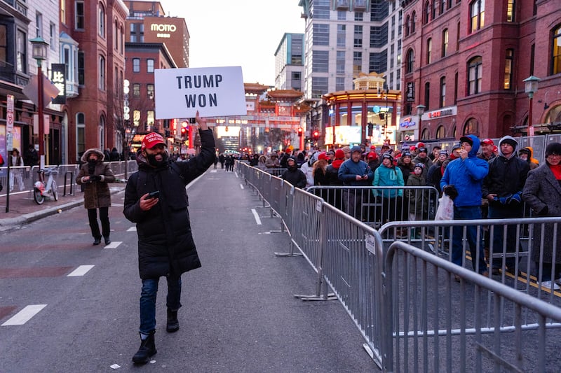 A smiling supporter of Donald Trump holds up a sign as others wait to enter the Capitol One Arena in Washington, DC on Monday. Photograph: Eric Lee/The New York Times
                      