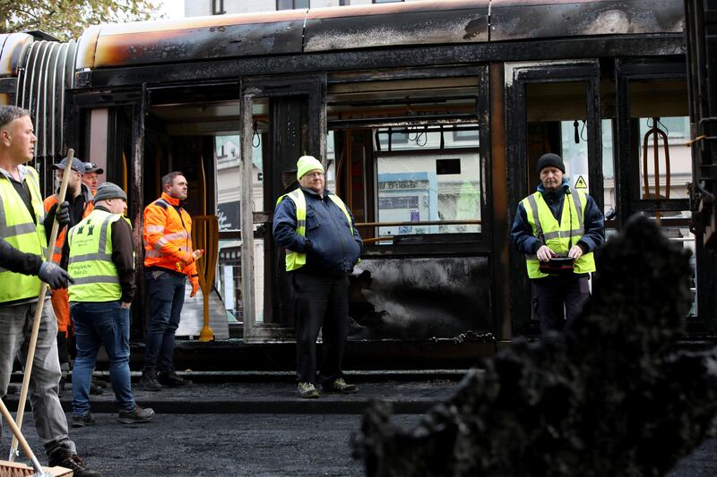 Workers look at the remains of a burnt out bus, as a fire-damaged Luas tram stands in the background, on O'Connell Street, Dublin on Friday. Photograph: Paul Faith/AFP/Getty