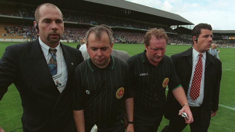 ClareReferee Jimmy Cooney (2nd from right) is led off the pitch after the game by security officials. Photograph: James Meehan/Inpho