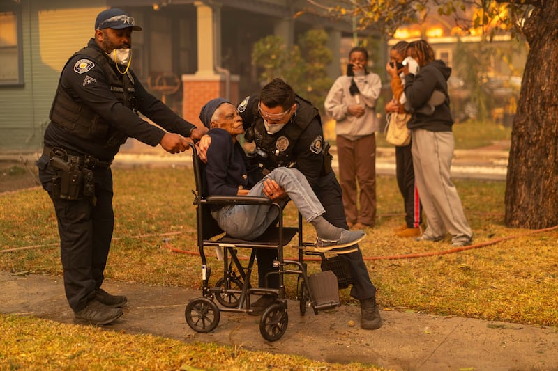 Laverna Sharpe, who is 101 years old, is carried from her home by Pasadena Police officer Christian Banuelos in Altadena, California. Photograph: Kyle Grillot/The New York Times
                      