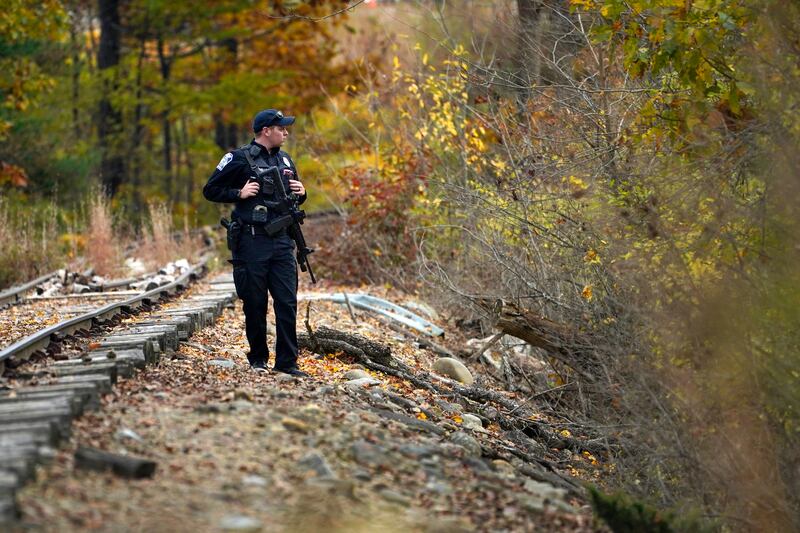 A police officer searches along railroad tracks near the Androscoggin River. Photograph: Robert F Bukaty/AP