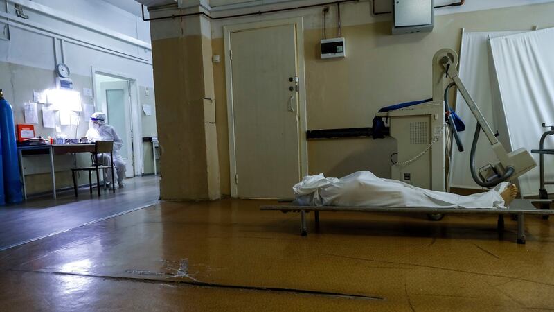 A medic wearing a special suit to protect against coronavirus fills documents as a body of a Covid-19 victim lies on a stretcher at an ICU of a hospital in Volgograd, Russia. Photograph: Alexandr Kulikov/AP Photo