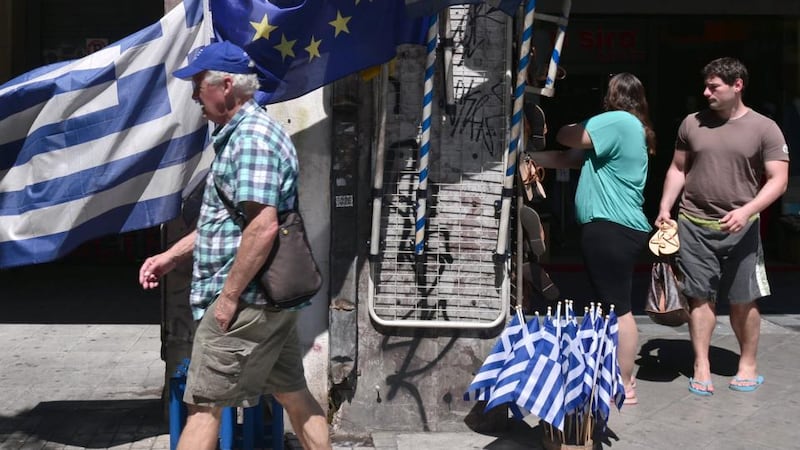 People walk past Greek and European Union flags on sale in Athens today. Photograph: Louisa Goulimaki/AFP/Getty