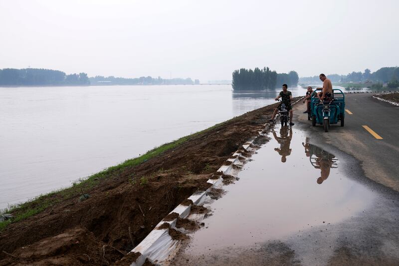 Villagers look over a swollen river which floods the crops at a village in Langfang in Hebei province, China. Photograph: Andy Wong/AP