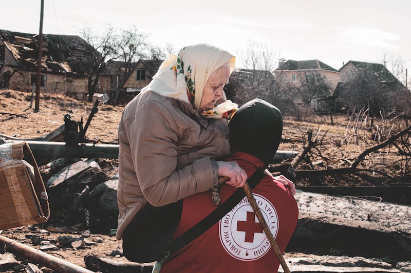 A Ukrainian Red Cross worker carries a woman towards safety near a destroyed bridge in the Kyiv suburb of Irpin, shortly after Russia's full-scale invasion of Ukraine in February 2022. Photograph: Oleksandra Kuvshynova/Ukrainian Red Cross