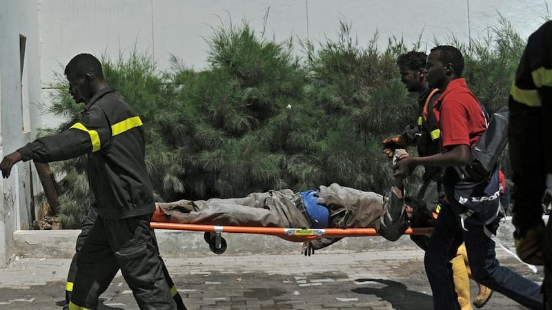 Paramedics carry an injured man on a stretcher outside the Central Hotel in Mogadishu, Somalia. Photograph: Mohamed Abdiwahab/AFP/Getty Images.