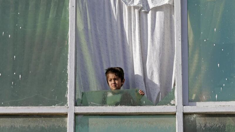 An Afghan child looks out from the broken window of a house near the site of an attack after a overnight battle outside a base in Kabul. Photograph: Mohammad Ismail/Reuters