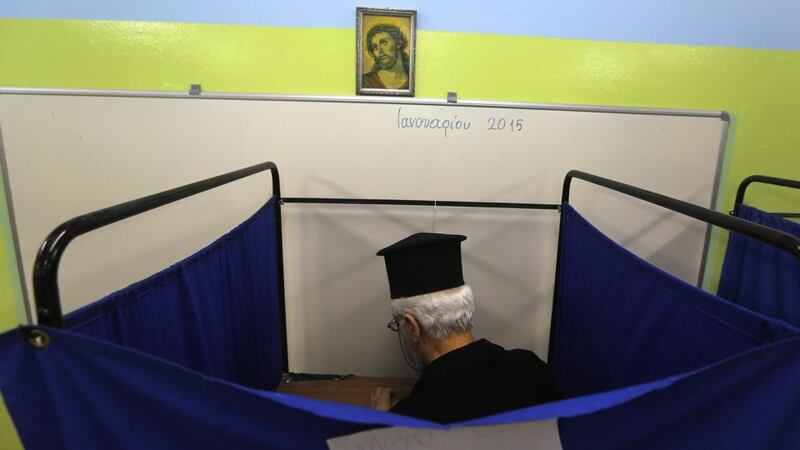 A Greek orthodox priest casts his vote inside a polling booth in an elementary school in Athens. Photograph: Yannis Behrakis/Reuters