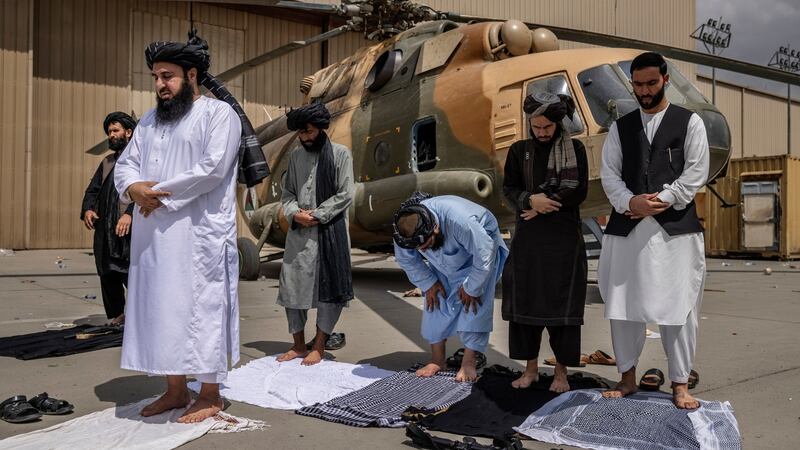 Members of the Taliban during prayer in front of a disabled helicopter at the airport in Kabul. Photograph: Victor J Blue/The New York Times