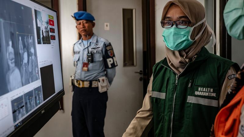 A health official monitors as passengers from an international flight have their temperature checked as they pass a thermal scanner monitor upon arrival at the Adisucipto International Airport  in Yogyakarta, Indonesia. Photograph: Ulet Ifansasti/Getty Images