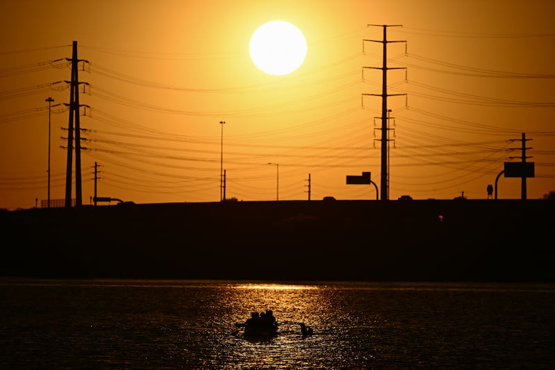 The sun sets behind power lines as people row on Tempe Town Lake during a record heatwave in Tempe, Arizona this month. Photograph: Patrick T Fallon/AFP via Getty Images