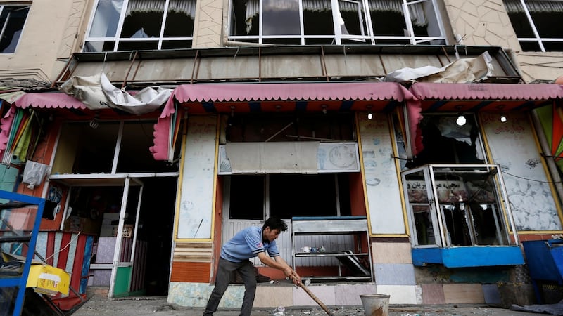 An Afghan man removes broken glass from his shop on Sunday, a day after a suicide attack in Kabul, Afghanistan. Photograph: Reuters