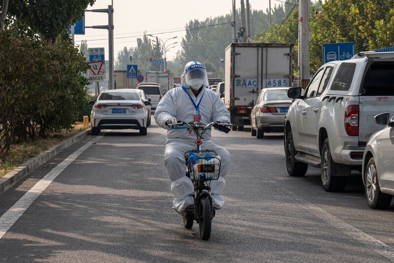 A worker wearing personal protective gear rides a scooter near an area placed under lockdown due to Covid-19 in Beijing. Photograph: Bloomberg