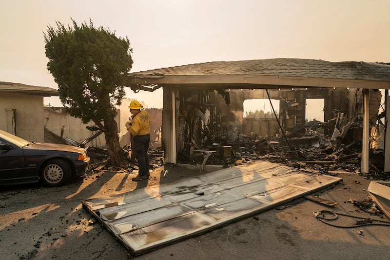 A firefighter looks for hotspots amid the rubble of a home. Photograph: Loren Elliott/The New York Times
                      