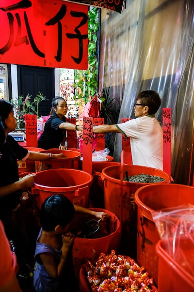 Street vendor in Singapore Chinatown selling melon seed to his customers. A big sign says "Melon Seed" in Chinese is handing above the stall.