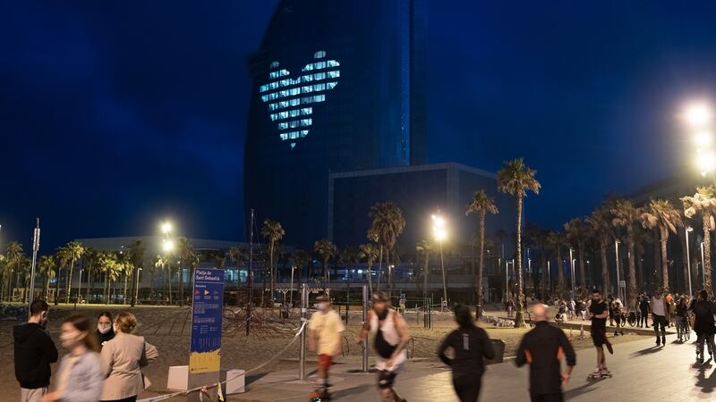 People exercise along the beachfront near the W Hotel, with a giant heart glowing on its facade, in Barcelona, Spain. Photograph: Samuel Aranda/The New York Times