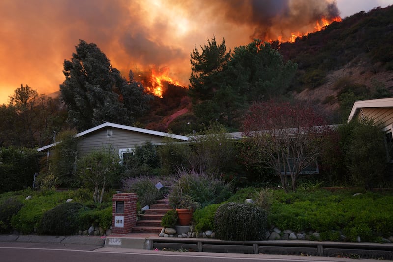 The Palisades fire burns above a home. Photograph: Eric Thayers/AP