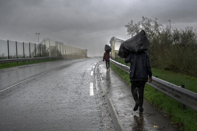 Migrants walk through heavy rain and carry their belongings in rubbish bags in Calais, France. Photograph: Christopher Furlong/Getty Images