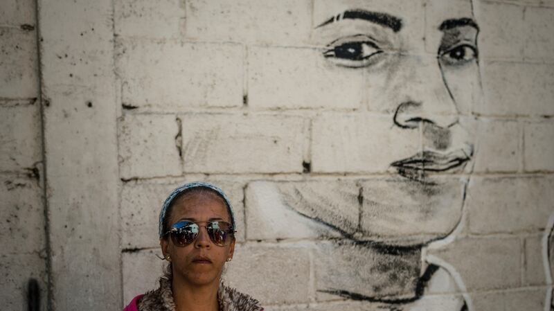 Nivea Pisani, Alixon’s aunt, beside the mural paying tribute to him in Catia, Caracas. Photograph: Meridith Kohut/The New York Times