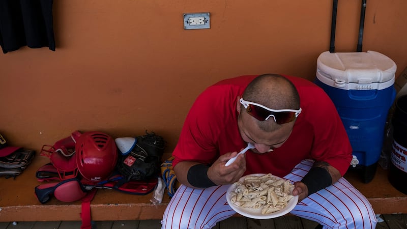 Cayey Toritos catcher Raulier Martinez eats in the dugout between games. Photograph: Dennis M Rivera Pichardo/The New York Times